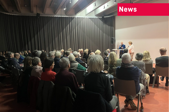 Das Bild zeigt das Publikum von hinten sowie Dr. Irene Bopp-Kistler und Carmen Frei auf der Bühne