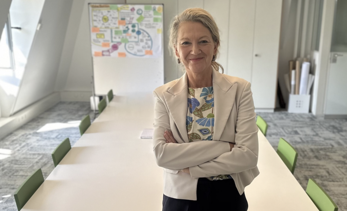 Renate Gurtner Vontobel in Business-Kleidung mit weissem Blazer und gemusterter Bluse, im Hintergrund das Sitzungszimmer des Vereins mit langem Besprechungstisch, Stühlen und Flipchart